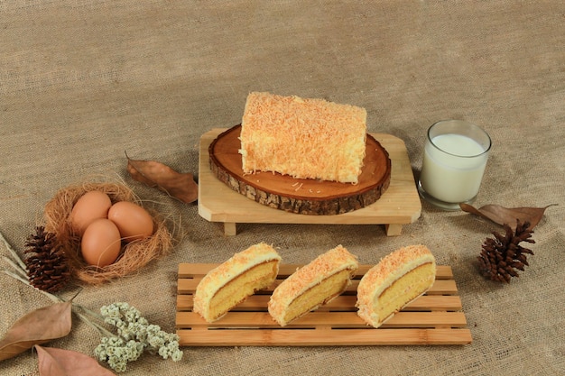 Una torta con sopra il cocco e un bicchiere di latte sul tavolo.