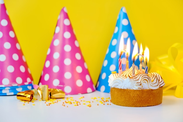 Una torta di compleanno colorata con candele e coriandoli su sfondo giallo