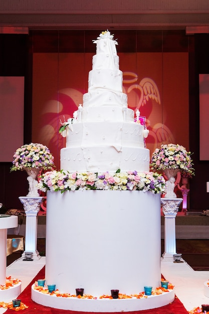 una torta nuziale multi-livello bianca su base argento e fiori rosa in cima