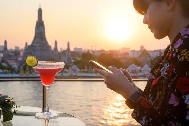 Una turista che beve un cocktail sul paesaggio urbano di Bangkok