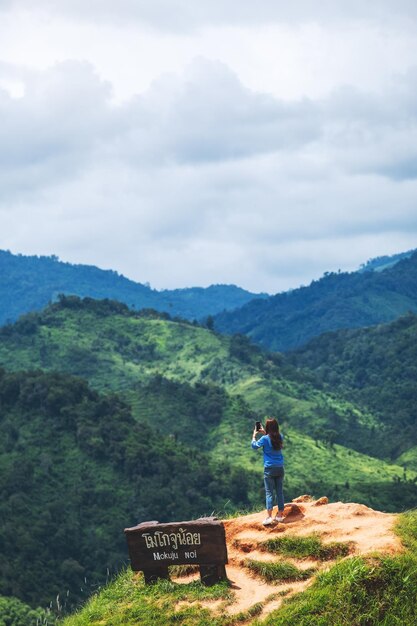 Una turista femminile che utilizza lo smartphone per scattare una foto di bellissime catene montuose