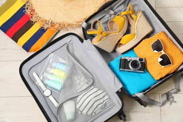 Una valigia aperta con le cose del viaggiatore sul pavimento.
