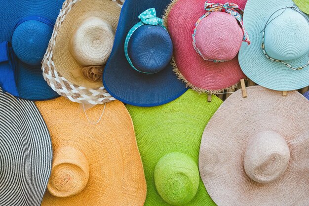 Una varietà di cappelli alla moda e colorati appesi sullo sfondo di bambù del negozio sul marciapiede