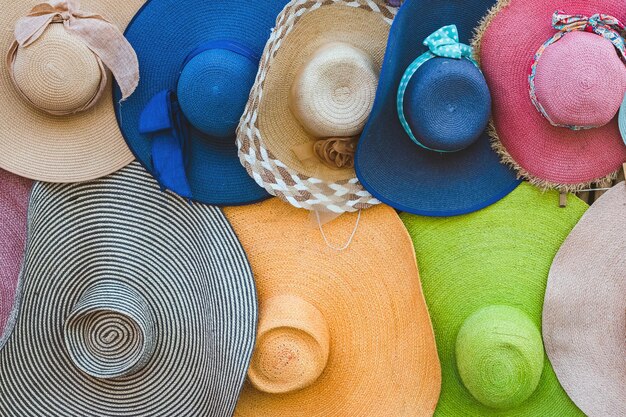 Una varietà di cappelli alla moda e colorati appesi sullo sfondo di bambù del negozio sul marciapiede