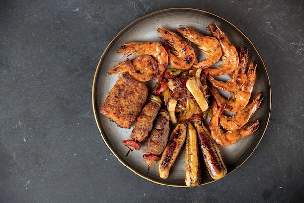 Una varietà di mix di frutti di mare alla griglia su un grande piatto di portata Gamberoni falangi di granchio Filetto di pesce Gamberetti