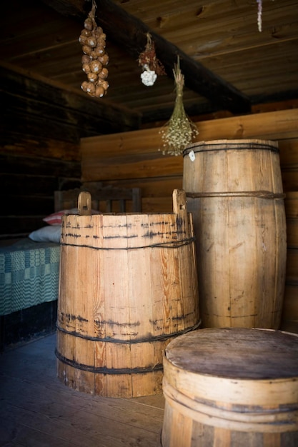 Una vecchia capanna di legno e un fienile fatto di tronchi rotondi Decorazione d'interni Botti pentole pentole di ghisa cesti di vimini ruote girevoli e fusi zangola