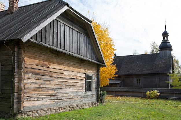 Una vecchia capanna di legno rustica. Sullo sfondo una chiesa rustica in legno. Foto di alta qualità