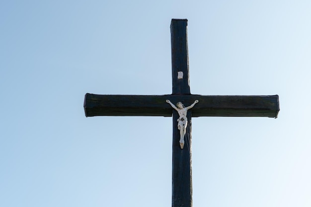 Una vecchia croce cristiana in legno contro un cielo azzurro in una bella giornata estiva Una statuetta di Gesù al centro della croce La crocifissione di Cristo La festa della Pasqua e della Resurrezione