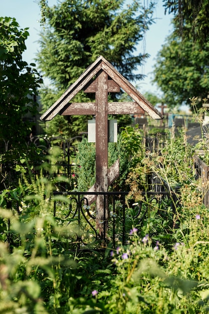 Una vecchia croce di legno su una tomba invasa. Memoria e dolore. Verticale.