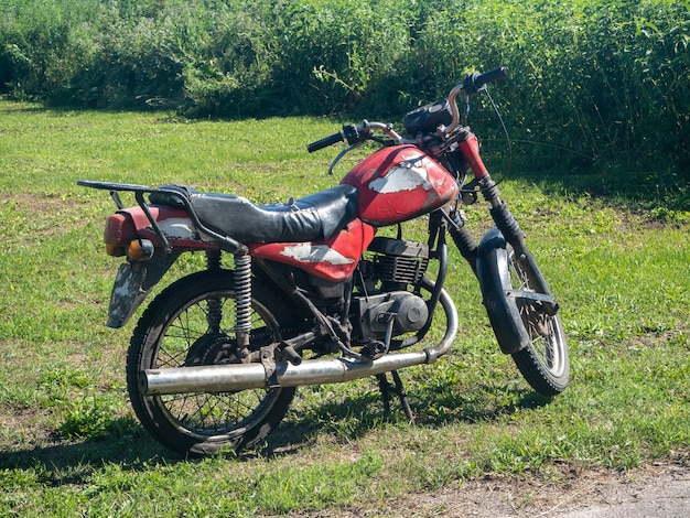 Una vecchia motocicletta rossa in una luminosa giornata estiva nel villaggio