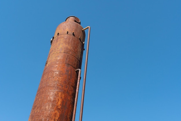 Una vecchia torre dell'acqua arrugginita in metallo Vecchia tecnologia di produzione che elabora l'essiccazione nel complesso agroindustriale Silo rosso sullo sfondo del cielo Costruzione in metallo