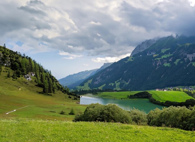 Una verde vallata con un lago e montagne sullo sfondo