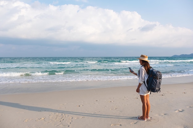 Una viaggiatrice che tiene e usa il telefono cellulare mentre viaggia verso il mare