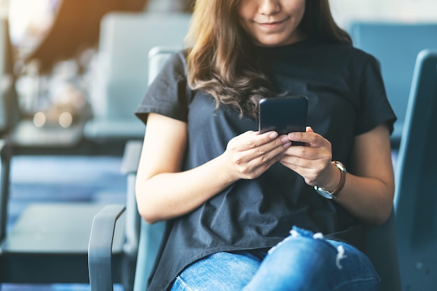 Una viaggiatrice che usa il cellulare mentre è seduta in aeroporto