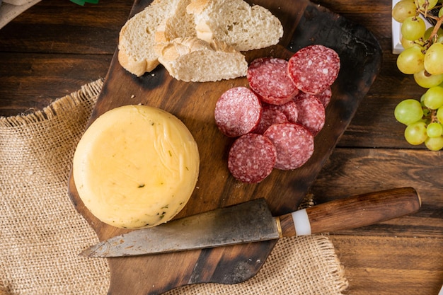 Una vista dall'alto di un delizioso pezzo di formaggio speziato su una tavola con pane e salame.