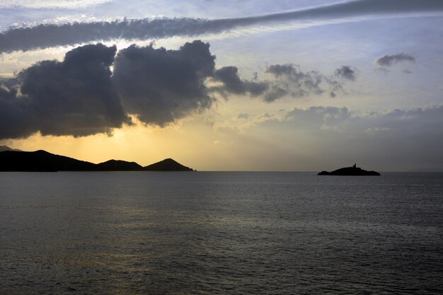 Una vista del mare calmo della sera e delle montagne in lontananza Lontano a destra c'è un'isola