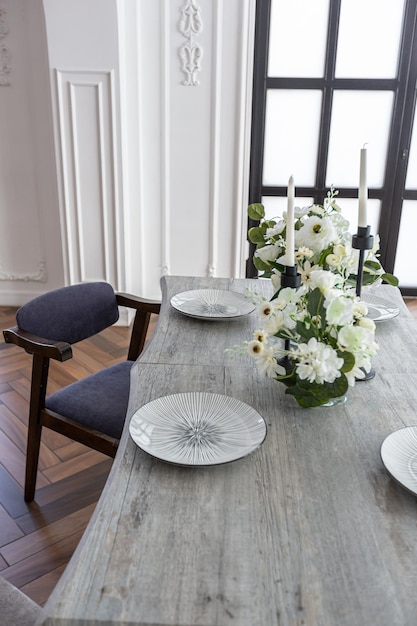 una vista di un tavolo da pranzo impostato in un elegante interno luminoso costoso di un enorme salotto in un palazzo storico con archi ad arco, colonne e pareti bianche decorate con ornamenti e stucco