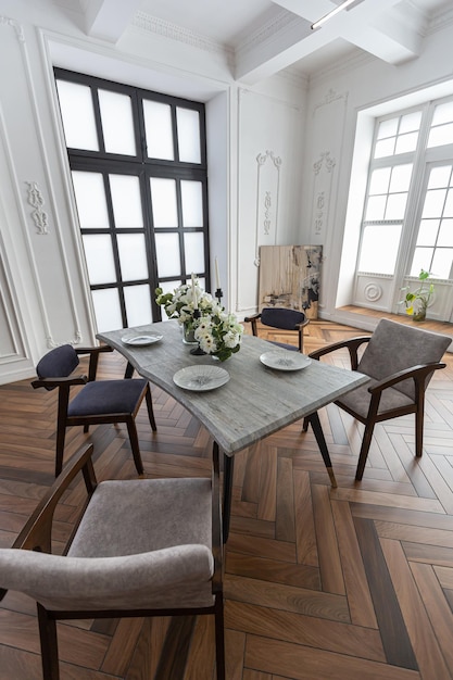 una vista di un tavolo da pranzo impostato in un elegante interno luminoso costoso di un enorme salotto in un palazzo storico con archi ad arco, colonne e pareti bianche decorate con ornamenti e stucco