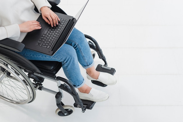 Una vista elevata della donna che utilizza computer portatile sulla sedia a rotelle