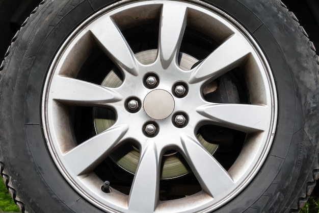 Una vista in primo piano di una ruota di un'auto con pneumatici invernali, disco freno argento e un cerchione a cinque dadi