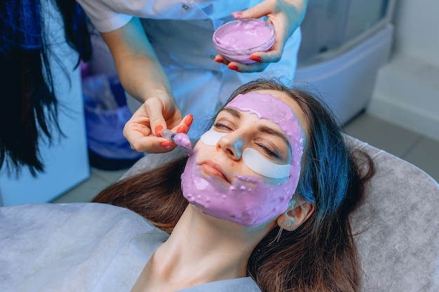 Una vista laterale di una giovane ragazza sdraiata su un divano con nutrienti e cerotti sotto gli occhi e una maschera su tutto il viso.