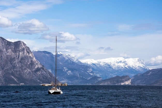 Una vista meravigliosa di uno yacht sul mare che naviga su uno sfondo pittoresco di alte montagne innevate