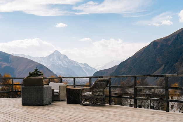 Una vista mozzafiato sulle maestose alte montagne ricoperte di neve bianca, veranda in legno e poltrone