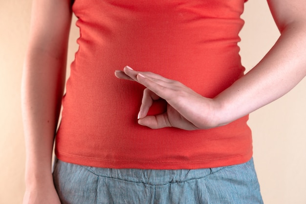 Una vista ravvicinata del ventre di una donna incinta in una maglietta rossa