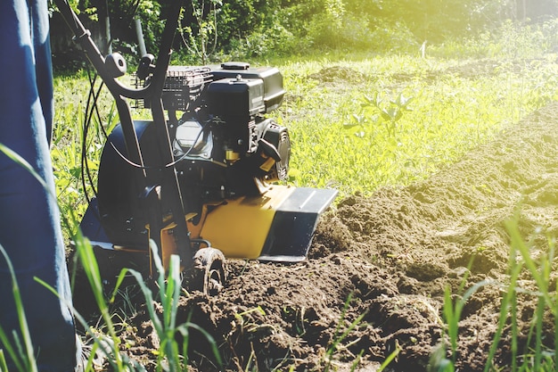 Una vista ravvicinata sul motocoltivatore durante il processo di aratro stagione primaverile concetto di lavori in giardino