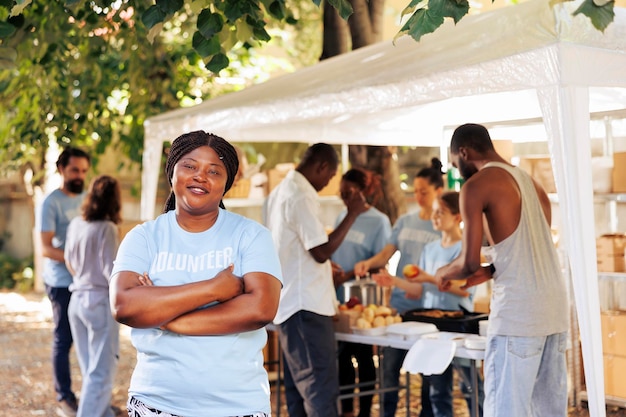 Una volontaria afroamericana sorride e posa a un evento senza scopo di lucro per la raccolta di cibo, un programma di iniziativa di beneficenza che fornisce soccorso alla fame e supporto ai senzatetto e a coloro che vivono in povertà.