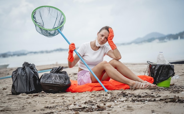 Una volontaria ecologista si sta riposando dopo aver ripulito la spiaggia in riva al mare da plastica e altri rifiuti