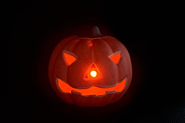 Una zucca intagliata incandescente in uno sfondo nero - concetto di halloween