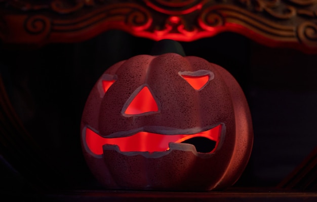 Una zucca intagliata incandescente in uno sfondo scuro - concetto di halloween