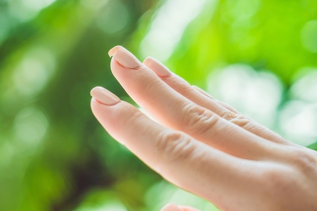 Unghia rotta sulla mano di una donna con una manicure su uno sfondo verde.