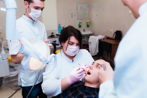 Università di Medicina. Il medico dentista insegnante professionista tratta i denti del paziente in ufficio su attrezzature moderne. Il concetto di formazione medica e trasferimento di esperienza.