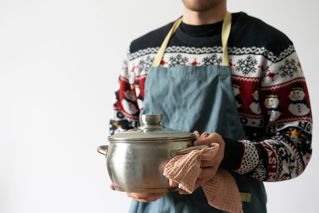 Uno chef in grembiule che cucina il piatto che tiene una pentola in cucina