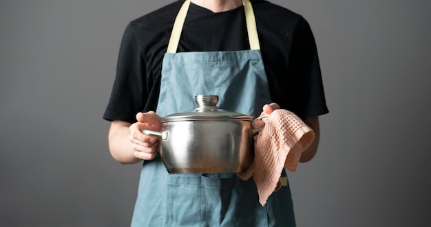 Uno chef in grembiule che cucina il piatto che tiene una pentola in cucina