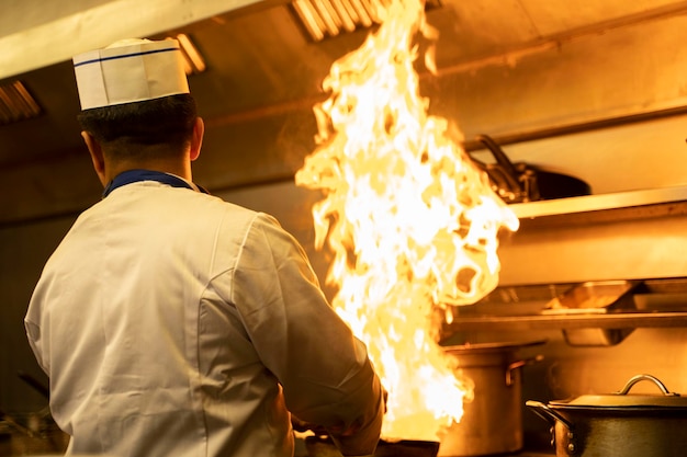 Uno chef nella cucina di un ristorante con le fiamme che escono
