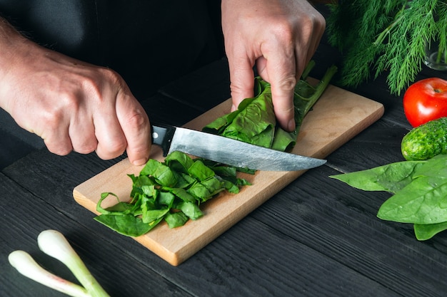 Uno chef prepara un'insalata di spinaci nella cucina di un ristorante