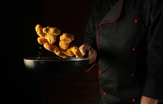 Uno chef professionista prepara nagit croccanti in padella Ricetta per cibi e piatti deliziosi su sfondo scuro Spazio pubblicitario gratuito