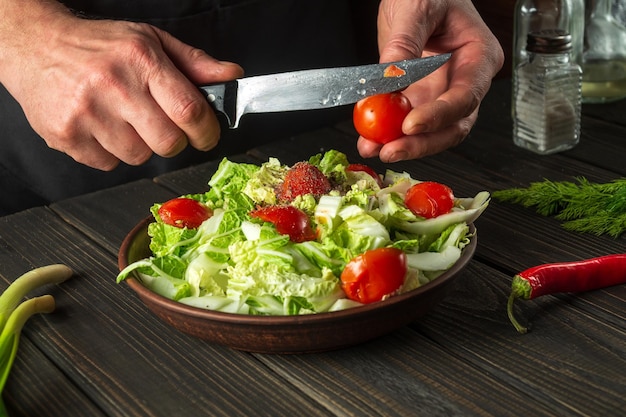 Uno chef professionista prepara un'insalata di verdure nella cucina del ristorante