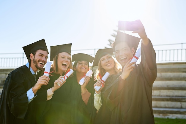 È uno dei momenti più luminosi che condivideranno insieme Foto di un gruppo di studenti che si fanno un selfie insieme il giorno della laurea