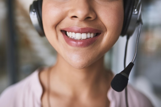 Uno deve mantenere un sorriso luminoso in ogni momento in questa linea di lavoro Inquadratura ritagliata di una donna d'affari allegra e irriconoscibile che parla con il cliente usando un auricolare