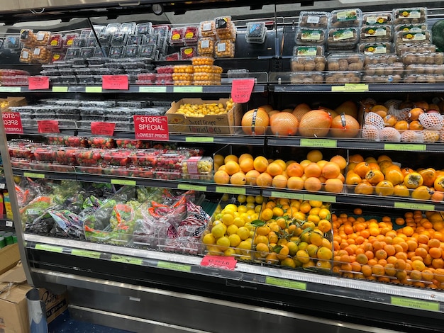 Uno scaffale di vetro per frutta con molti frutti freschi al mercato