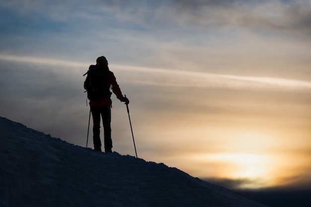 Uno sciatore di alpinismo osserva il tramonto