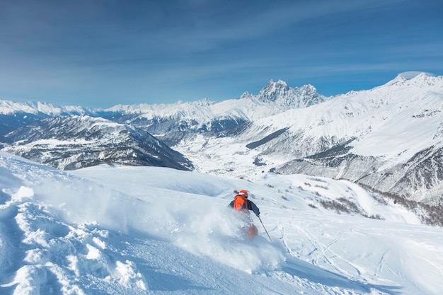 Uno sciatore fa freeride sullo sfondo delle cime del Monte Ushba, la Grande Catena Caucasica in inverno