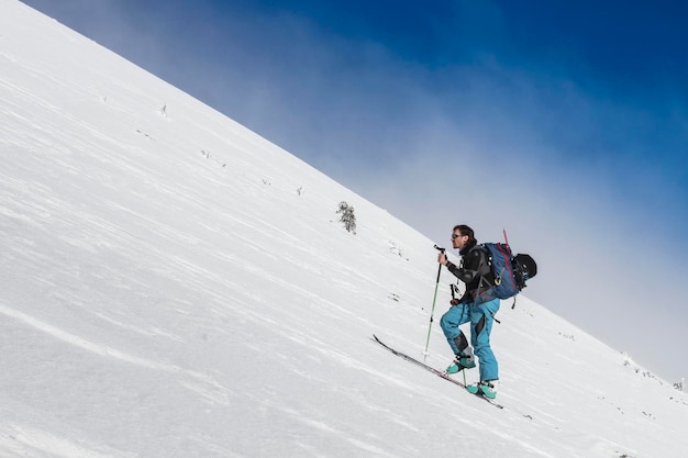 Uno sciatore sciatore si arrampica su un pendio innevato