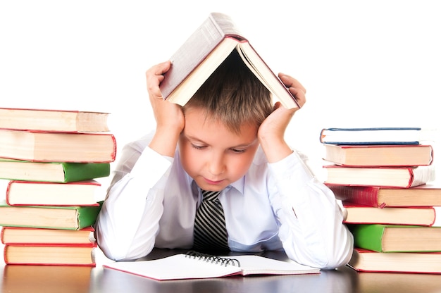 Uno scolaro stanco e in ritardo si siede in una biblioteca con libri e impara le lezioni. Riluttanza ad imparare.