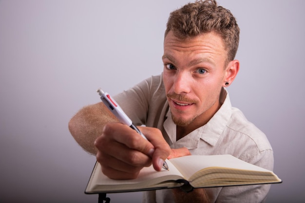 Uno scrittore tiene in mano una penna e scrive in uno studio di agenda girato con uno sfondo bianco
