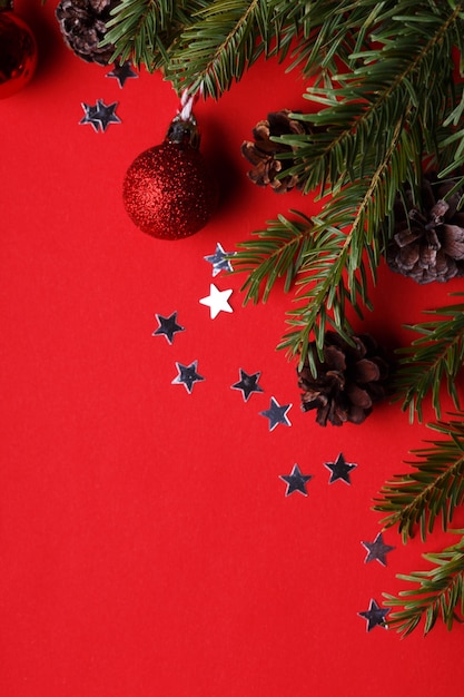 Uno sfondo di natale Ramoscelli di albero di Natale Palle e coni di Natale su uno sfondo rosso